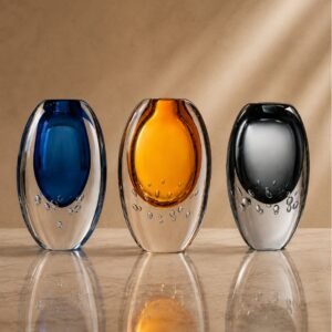 Luxury three-piece art glass sculpture set featuring blue, amber, and black decorative glass accents displayed on a designer shelf.