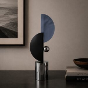 Modern abstract geometric sculpture featuring intersecting black and blue semicircular forms, a polished metallic sphere, and a cylindrical base displayed in a contemporary luxury interior.