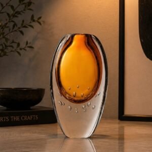Luxury amber art glass vase with a glowing amber core, crystal-clear outer layer, and decorative bubble detailing, displayed as an elegant centerpiece in a sophisticated modern interior.