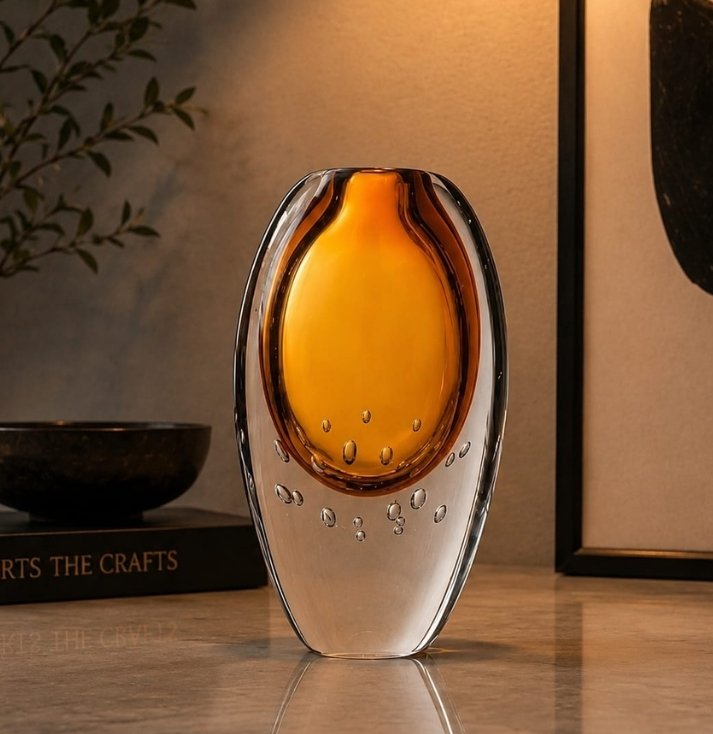 Luxury amber art glass vase with a glowing amber core, crystal-clear outer layer, and decorative bubble detailing, displayed as an elegant centerpiece in a sophisticated modern interior.