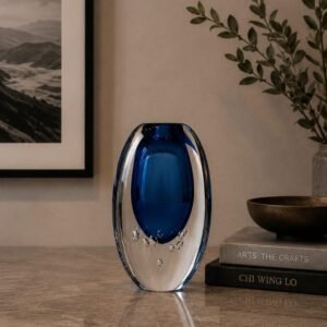 Luxury sapphire-blue art glass vase with a crystal-clear outer layer and decorative bubble detailing, displayed as a sophisticated contemporary centerpiece in an elegant modern interior.