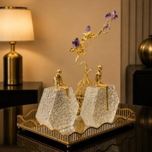 Luxury decorative centerpiece featuring gold figurines seated on crystal-textured blocks with an amethyst crystal blossom tree on a gold tray.