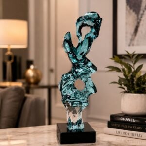 Luxury aqua crystal glass sculpture with flowing abstract organic forms mounted on a black pedestal, displayed as a contemporary decorative centerpiece in an elegant modern interior.