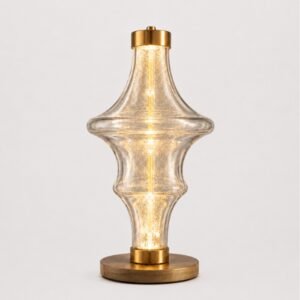 Luxury sculptural glass table lamp with a transparent art glass body, warm glowing illumination, and brushed gold accents, designed for elegant contemporary interiors.