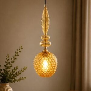 Luxury amber crystal pendant light with a faceted textured glass shade, decorative crystal finial, gold accents, and warm ambient illumination in a sophisticated contemporary interior.
