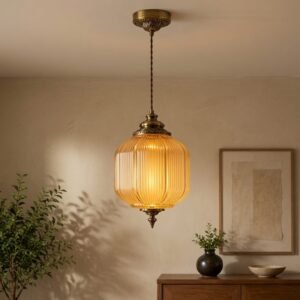 Luxury amber ribbed glass pendant light with antique brass finish and warm golden illumination.